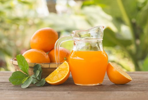 Orange juice is placed on a wooden table with natural light.