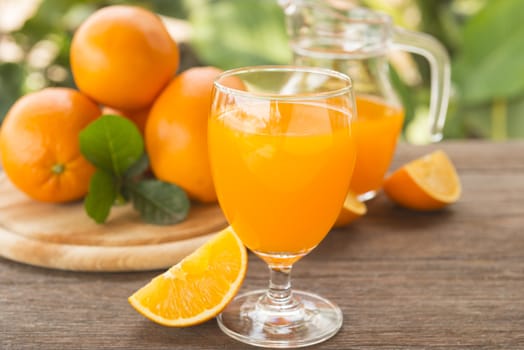 Orange juice is placed on a wooden table with natural light.