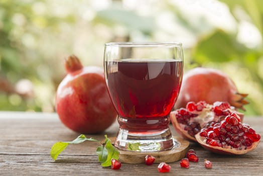 glass of pomegranate juice with fresh fruits on wooden table.