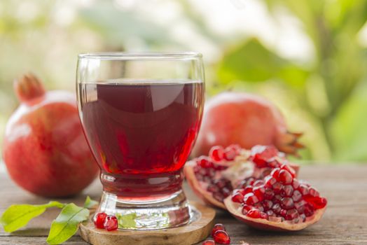 glass of pomegranate juice with fresh fruits on wooden table.