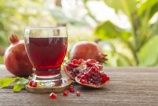 glass of pomegranate juice with fresh fruits on wooden table.