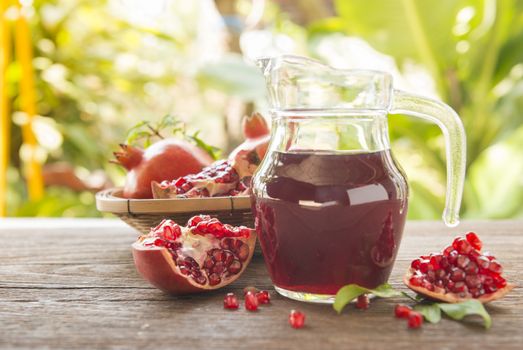 Jug of pomegranate juice with fresh fruits on wooden table. - soft focus.