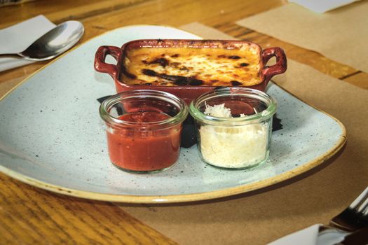 Classical Italian cuisine - Lasagna with meat in a clay bowl with grated tomatoes and Parmesan cheese