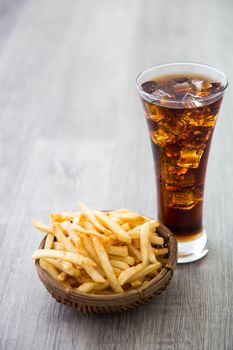 a bucket of french fried with soft drink on wooden table