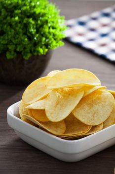 Bowl of potato chip on wooden table