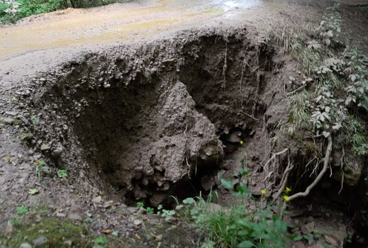 The collapsed edge of the road from the rain. Akyduct for water runoff.