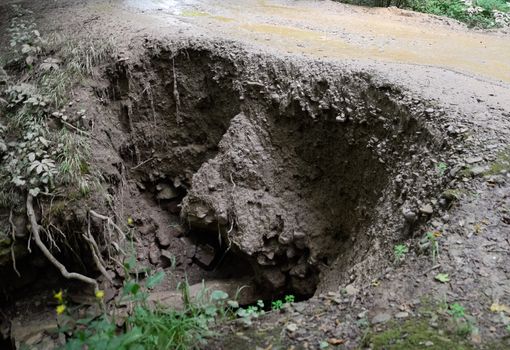 The collapsed edge of the road from the rain. Akyduct for water runoff.