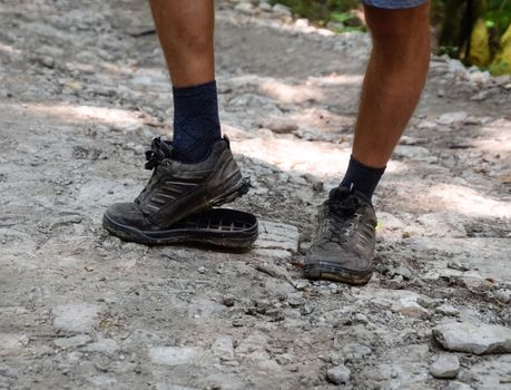 The detached sole on the tourist's sneakers. They broke their boots in the woods.