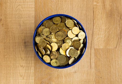bowl of gold coin on wooden background