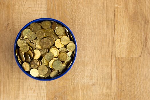 bowl of gold coin on wooden background
