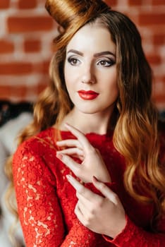 young girl with red hair in a bright red dress in a bright room on an antique sofa