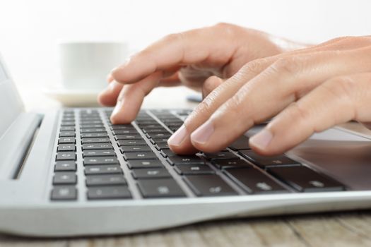 Hands writing on a laptop keyboard in the office in close-up