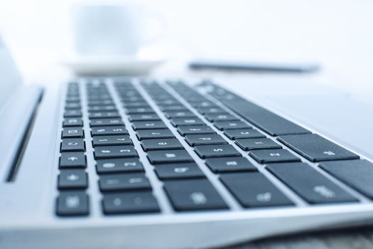 Laptop on the desk in the office in close-up - very low DOF and light blue filter- perfectly for technological background.