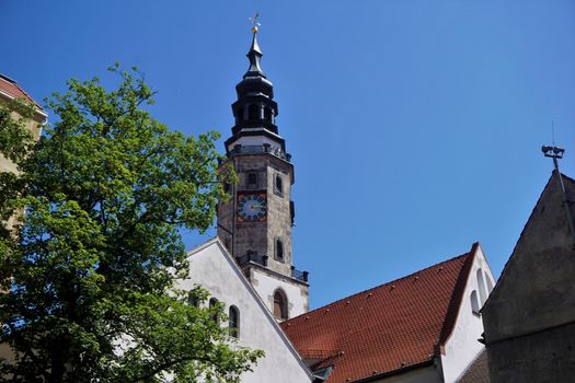 Watch tower of the Goerlitz city hall behind roof tops with tree and blue sky