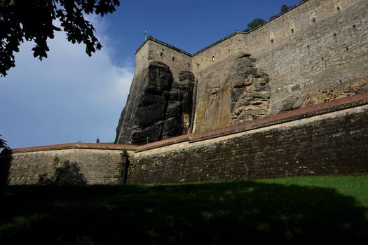 Meadow in front of massive wall with Elbsandstone rocks spotted in Koenigstein