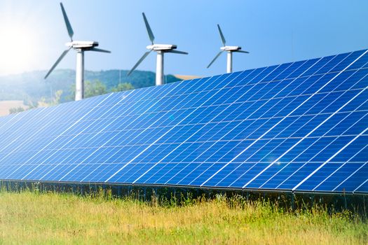 Composite image of renewable energy sources - solar farm for photovoltaic energy and windmills for wind energy