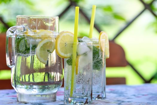 Cool and refreshing drink with lemon, mint and ice in the garden on a hot day.