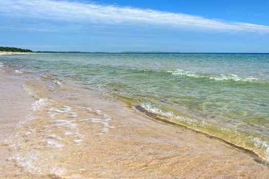 Beautiful landscape of sandy sea coast on the blue sky background.