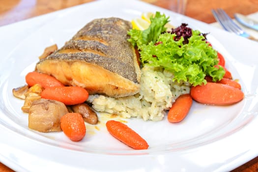 Delicious fried fish Halibut served sweet with carrots, pear, rice, lettuce and lemon.