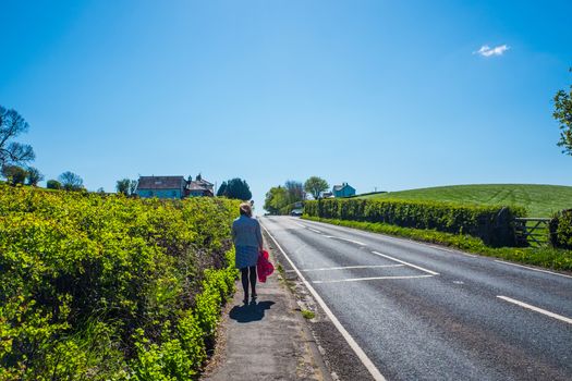 Brunette walking away from camera carrying a coat UK