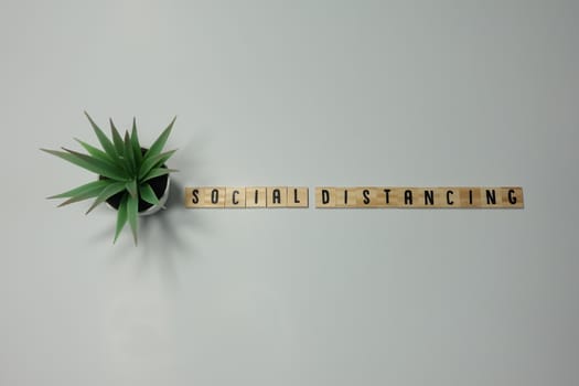 The word Social Distancing written in wooden letter tiles on a white background.  Concept protection, coronavirus, and contamination.