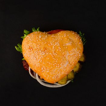 Heart shape burger cheeseburger hamburger, love burger fast food concept, on black background, top view flat lay