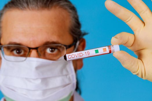 Coronavirus Covid 19 infected blood sample in sample tube in hand of doctor in face mask