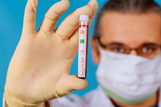Tube infected blood sample in hand with coronavirus Covid 19