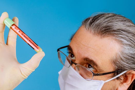 Doctor in face mask a blood test tube sample to check COVID-19 coronavirus