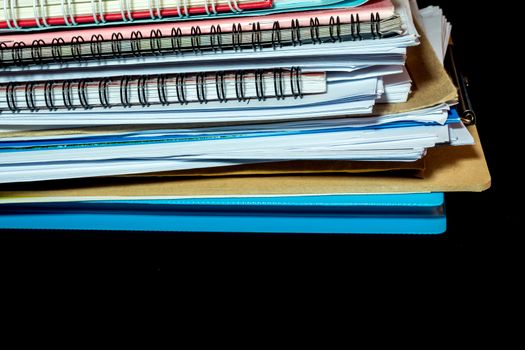 Stacked of office documents paper and notebook in the black background