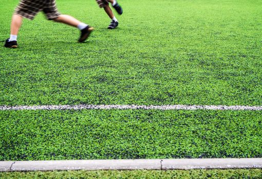 Children play on the artificial turf of the school