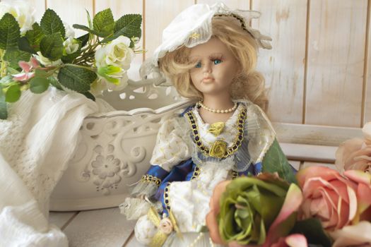 Still life in vintage style with a doll, pastel roses on a shabby background of old wooden planks