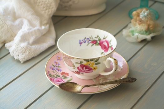 Pink vintage porcelain tea cup on turquoise table.
