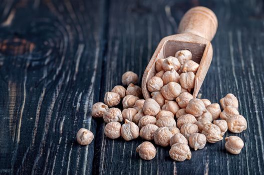 Dry chickpeas in scoop on wooden table