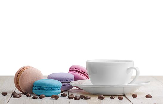 Macaroons with coffee on a wooden table with coffee grains on white background