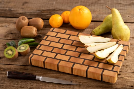 Juicy whole and sliced fruit with a knife on a wooden cutting board