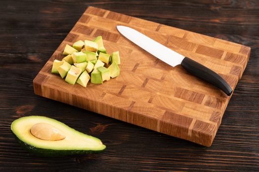 Avocado sliced with cube using knife on wooden cutting board