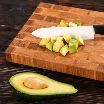 Avocado sliced with cube using knife on wooden cutting board