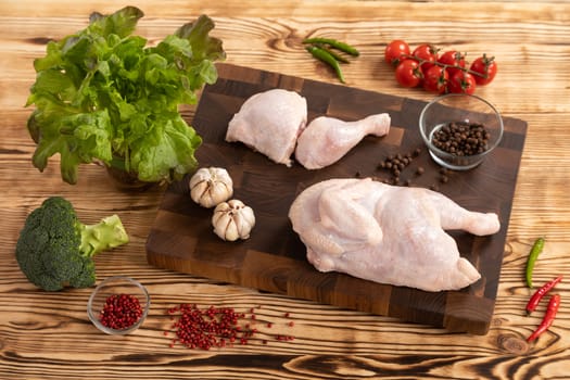 Raw chicken and vegetables for cooking lie on a wooden cutting board