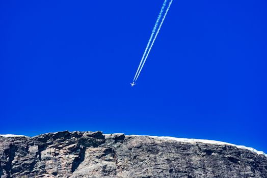 Airplane trail in the blue sky over mountain