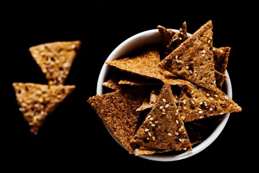 Sesame triangular crispy chips in bowl top view