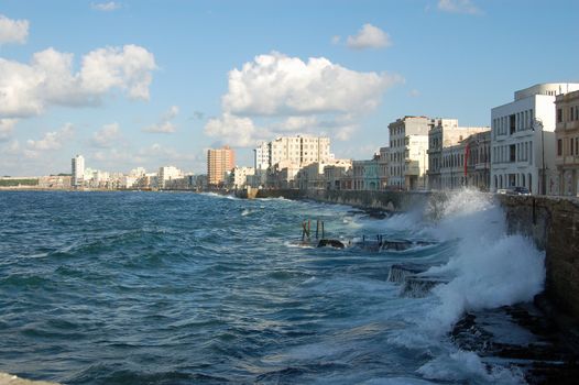 Waves from the Caribbean Sea crashing against the wall of the Malecon promenade in Havana, Cuba on a sunny evening.