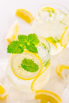 Lemonade drink in a glass: water, ice, lemon slice and mint