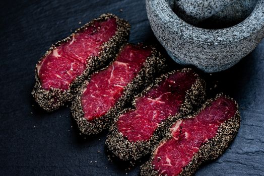 Pepper steaks on stone with mortar bowl and pestle