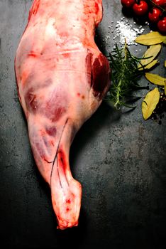 Raw lamb leg with spices for cooking on dark grange background