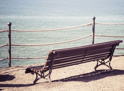 Empty wooden bench on the beach. Concept of loneliness, emptiness, solitude.