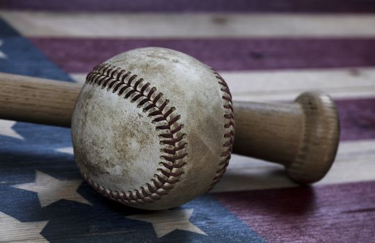 Closeup view of an old baseball and traditional wood bat on rustic wooden United States Flag