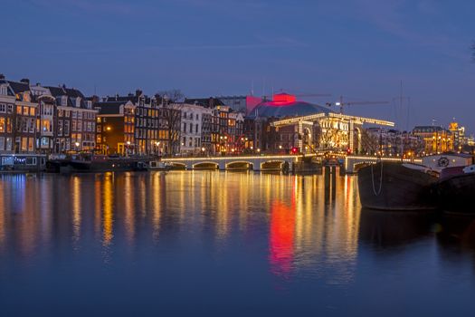 City scenic from Amsterdam at the river Amstel with the Tiny bridge in the Netherlands at night