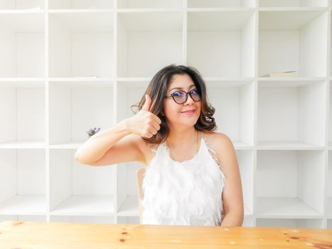 Beautiful woman smiling happy against white background with wood table and good attitude.