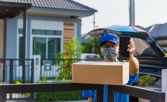 Asian delivery man courier Place deliveries boxes at home and showing mobile phone blank screen for customer sign he protective face mask service under curfew quarantine pandemic coronavirus COVID-19